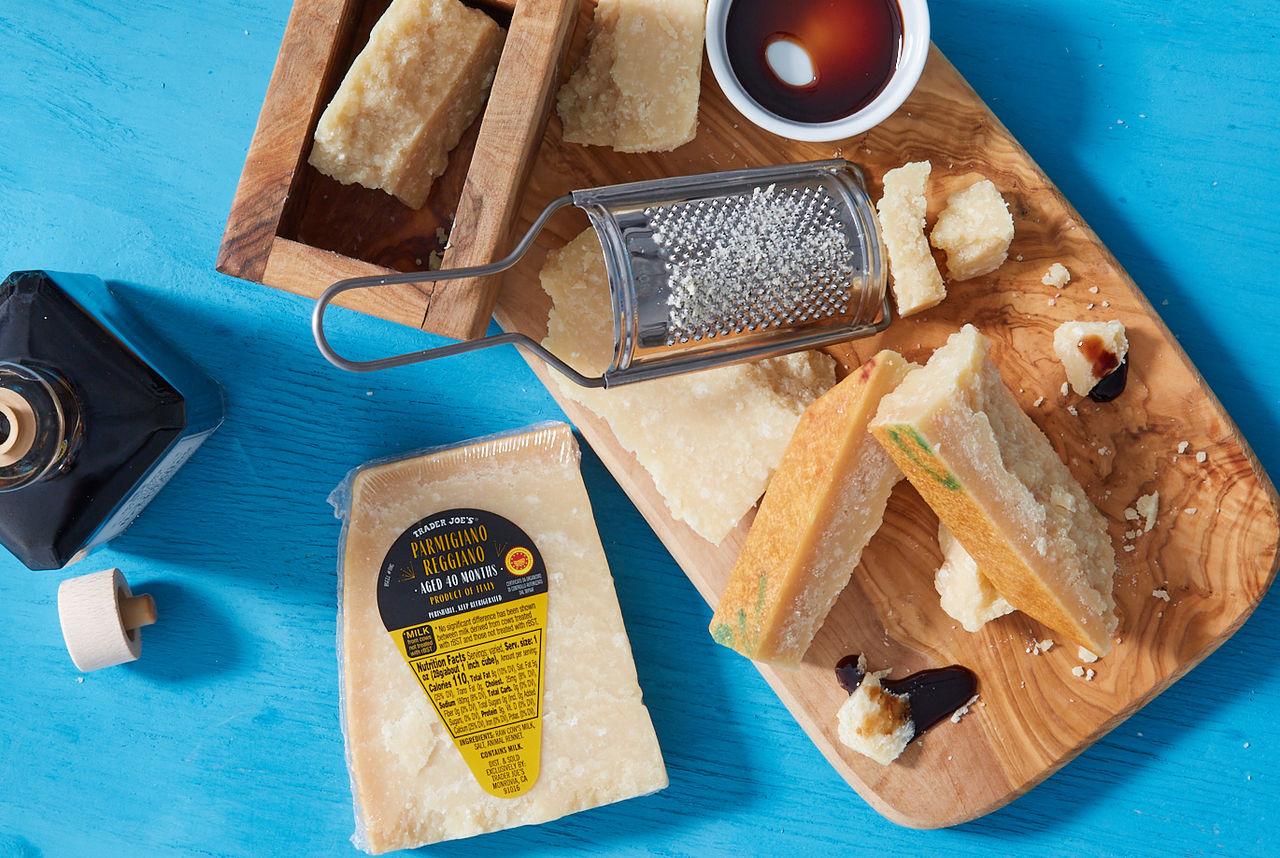 Trader Joe's Parmigiano Reggiano aged 40 Months; pieces broken on wood board, and grated with mini cheese grater; balsamic vinegar drips on a couple pieces