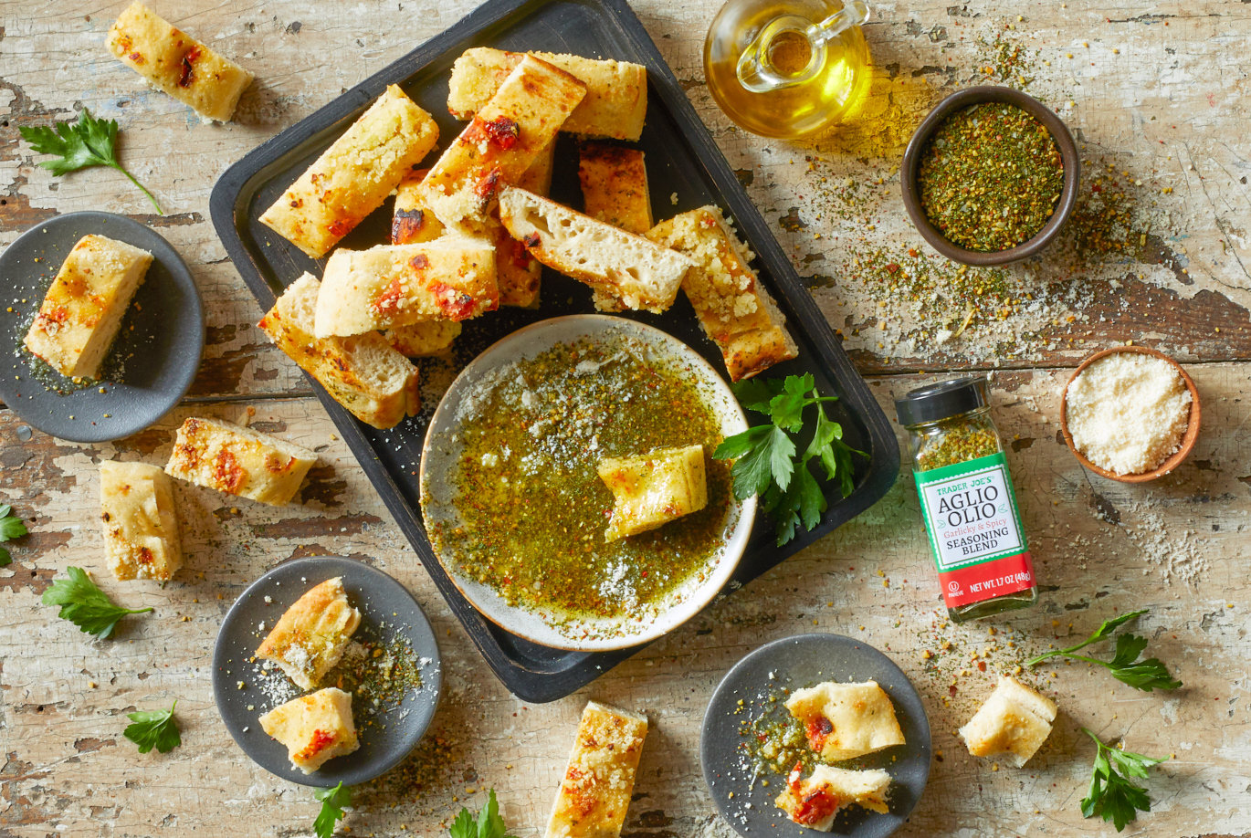 Trader Joe's Aglio Olio Seasoning Blend; used in recipe for Garlicky Parmesan Spice Dip; in small dish with oilive oil and slices of focaccia bread; several small plates with bread and dip; spices surrounding