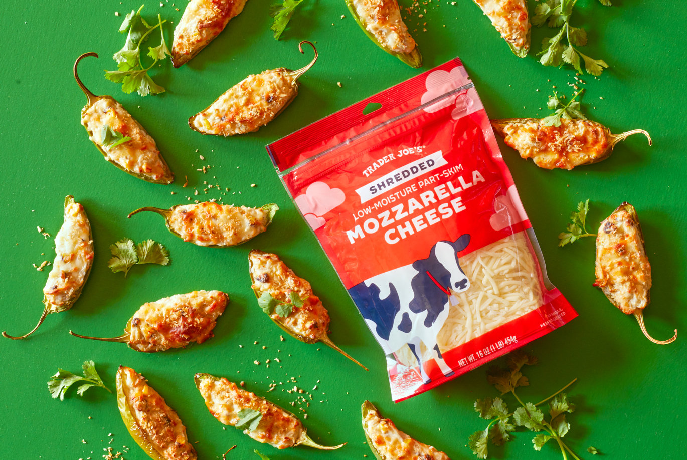 Trader Joe's Shredded Mozzarella Cheese; used in recipe for JalapeÃ±o Corn Kick Poppers; on green surface, jalapeÃ±o poppers surrounding package